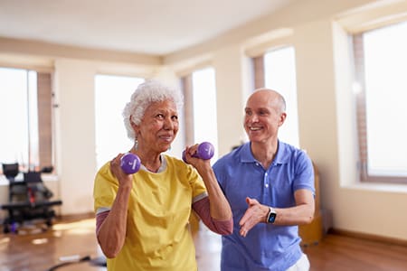 Senior woman doing weight training with assistance
