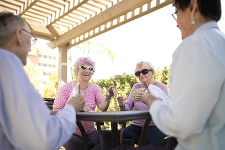 Group of residents playing cards at an outdoor table