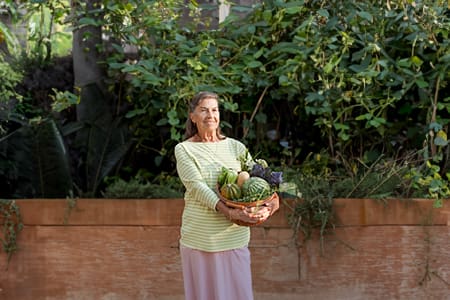 Portrait of woman holding basket of fresh vegetables