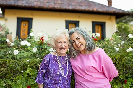 Portrait of two smiling women outside of a home