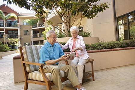 Senior man and women sitting outdoors and looking at a tablet