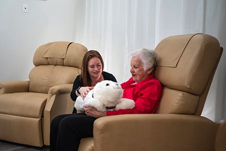 Senior woman holding large stuffed animal in char