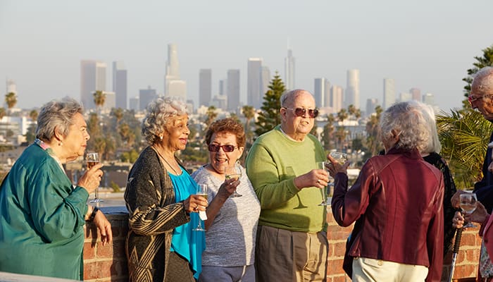 Portrait of a smiling group enjoying the Kingsley Manor rooftop with view of Los Angeles