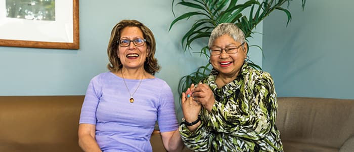 Smiling women holding hands on couch