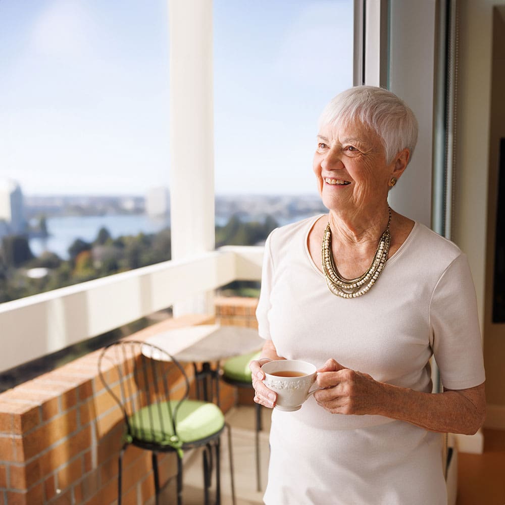 Portrait of senior woman drinking tea outside window at St. Paul's Towers