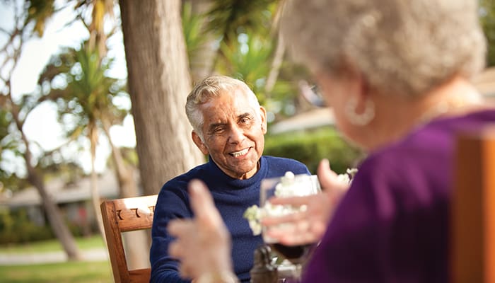 Portrait of a senior man smiling as a woman talks to him