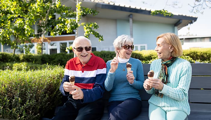 Portrait of senior residents gathering outside and talking while enjoying ice cream at Wesley Palms