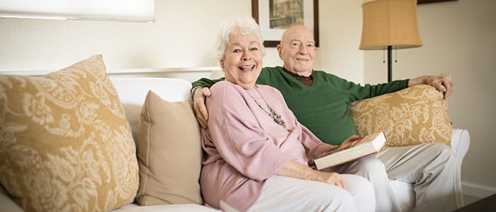 Portrait of smiling senior man and woman sitting on the couch at Carlsbad by the Sea