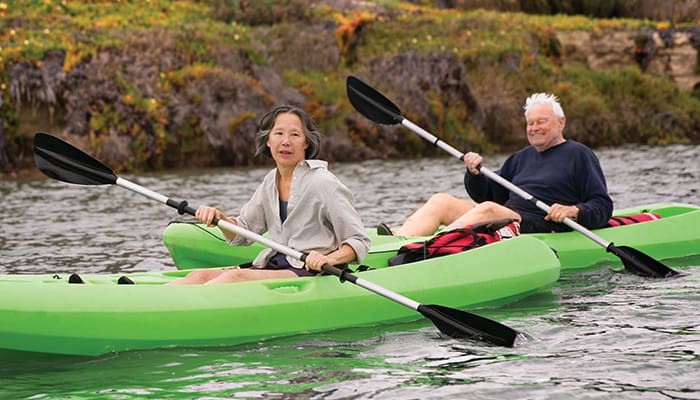 Senior residents rowing in green kayaks