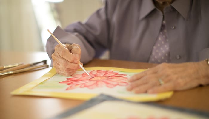 Closeup of a senior woman painting a flower