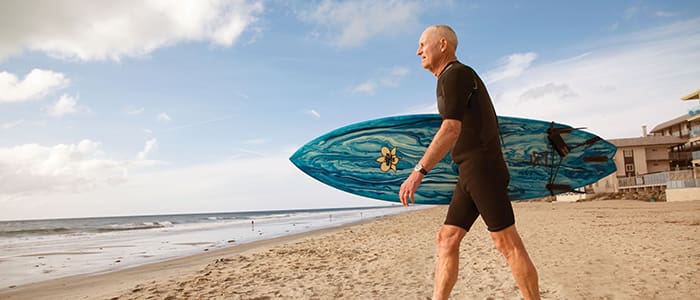 Senior man with surfboard in hand at the beach