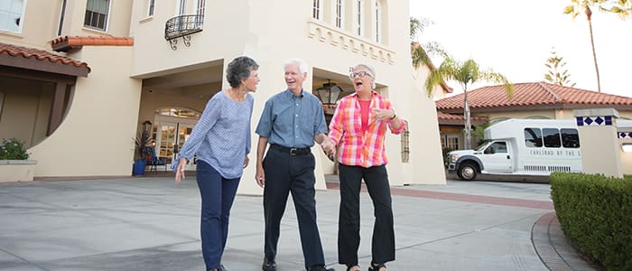 Senior residents walking and talking outside the entrance of Carlsbad by the Sea