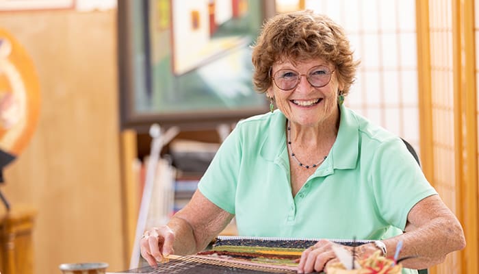 Portrait of senior woman weaving at Friends House