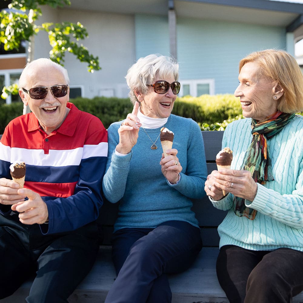 Portrait of senior residents gathering outside and talking while enjoying ice cream at Wesley Palms