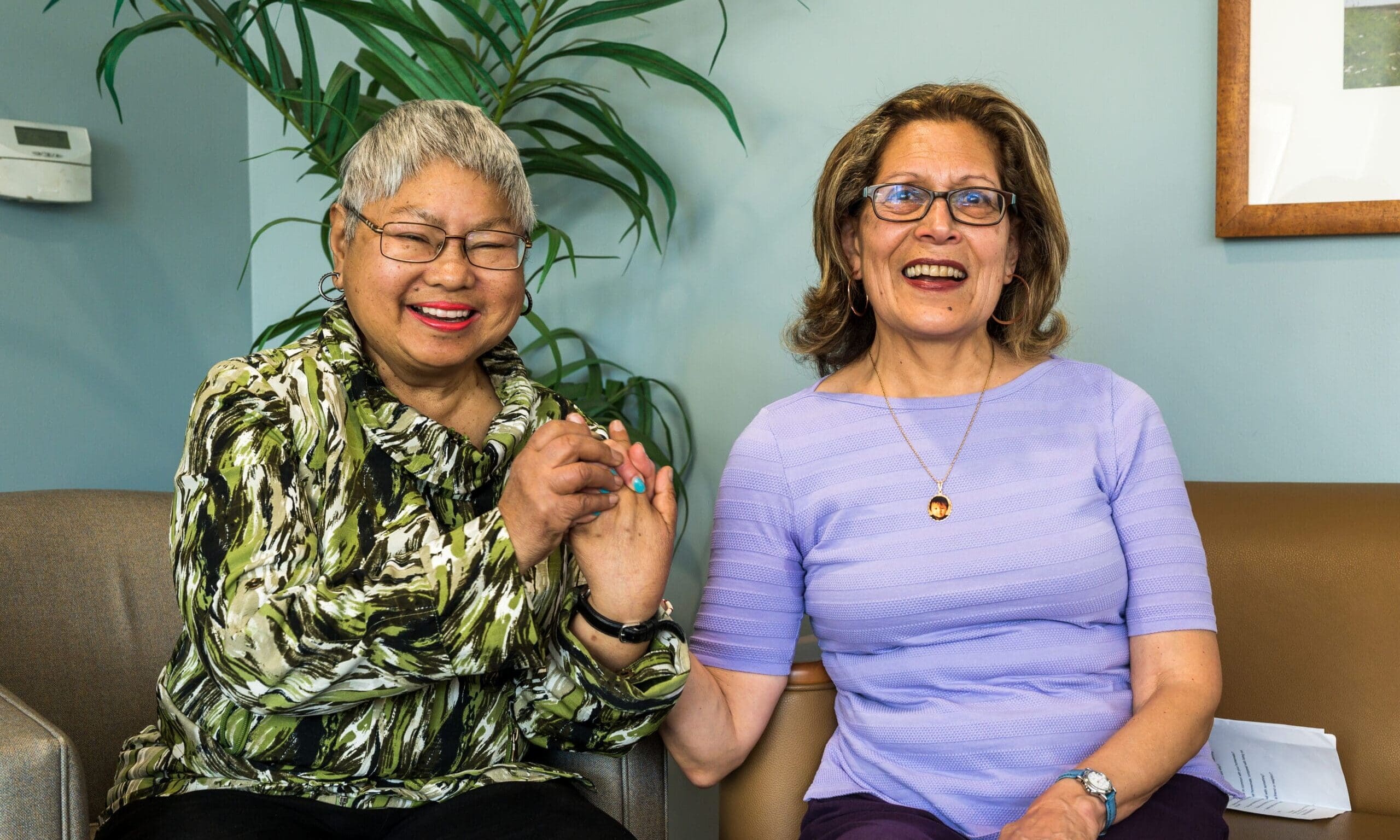 Two women smile and hold hands