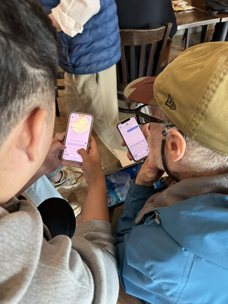 Younger and older person sit next to one another with smart phones