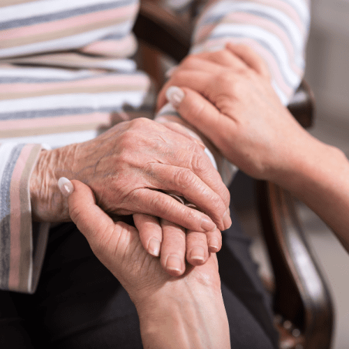 Elderly man holding womans hand for comfort