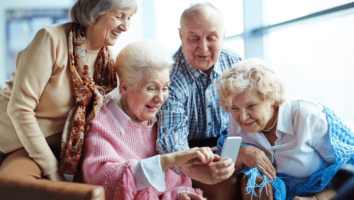 a group of seniors looking at a cell phone and smiling