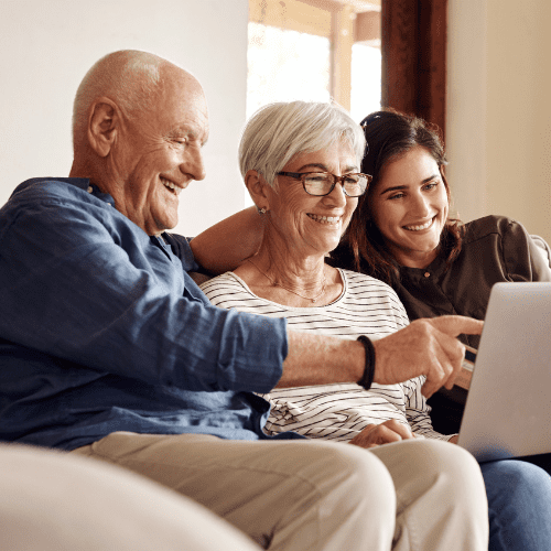 daughter looking at a computer on the couch with her elderly parents