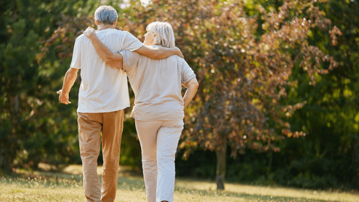 an elderly couple walking in each other's arms