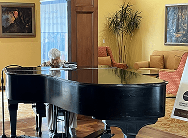 A woman plays the piano in a large room.