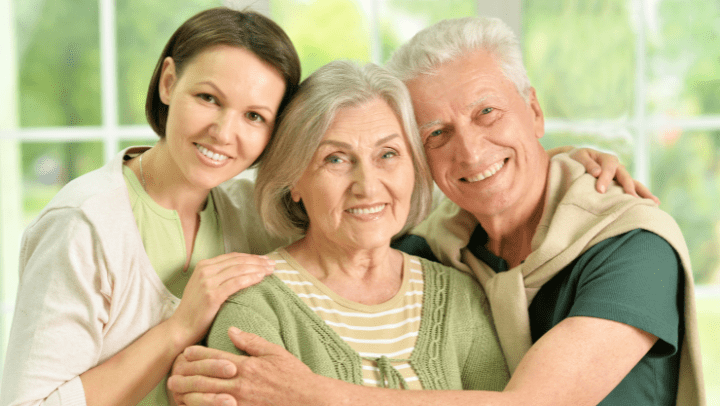 a senior couple with their daughter hugging each other