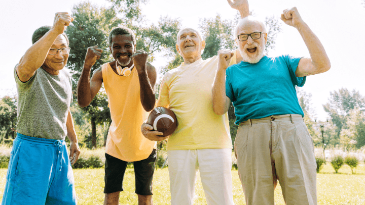 A group of older adults cheer while standing outside.