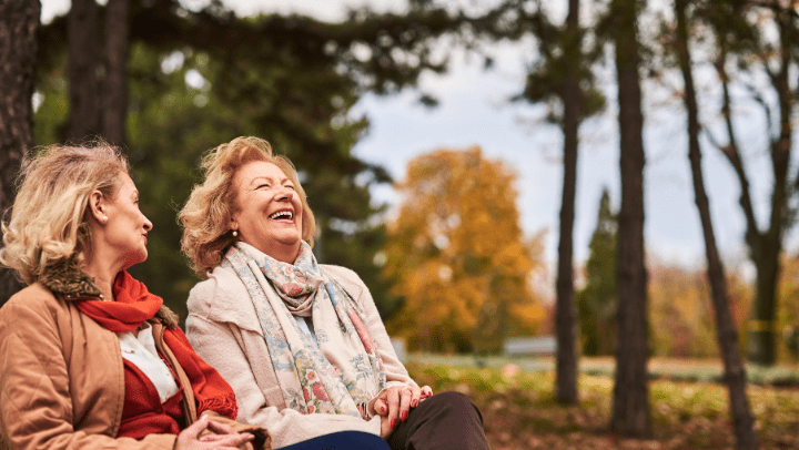 Two women laugh outside in Autumn.