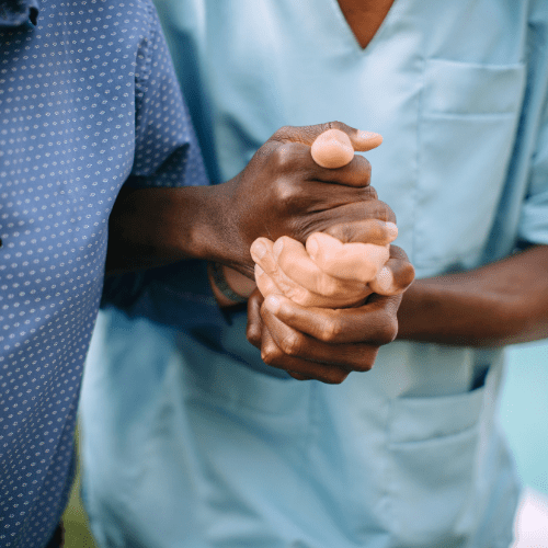 Nurse helping elderly man by holding his hand