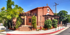 Red brick chapel building with red roof under blue sky