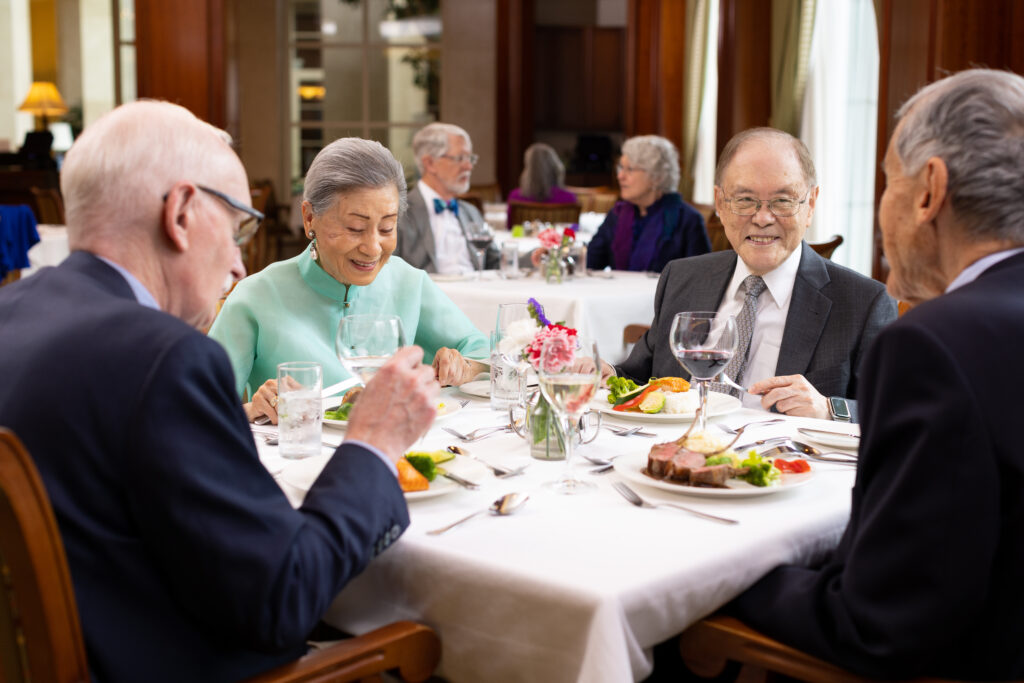 a group of seniors smiling at each other while enjoying their dinner