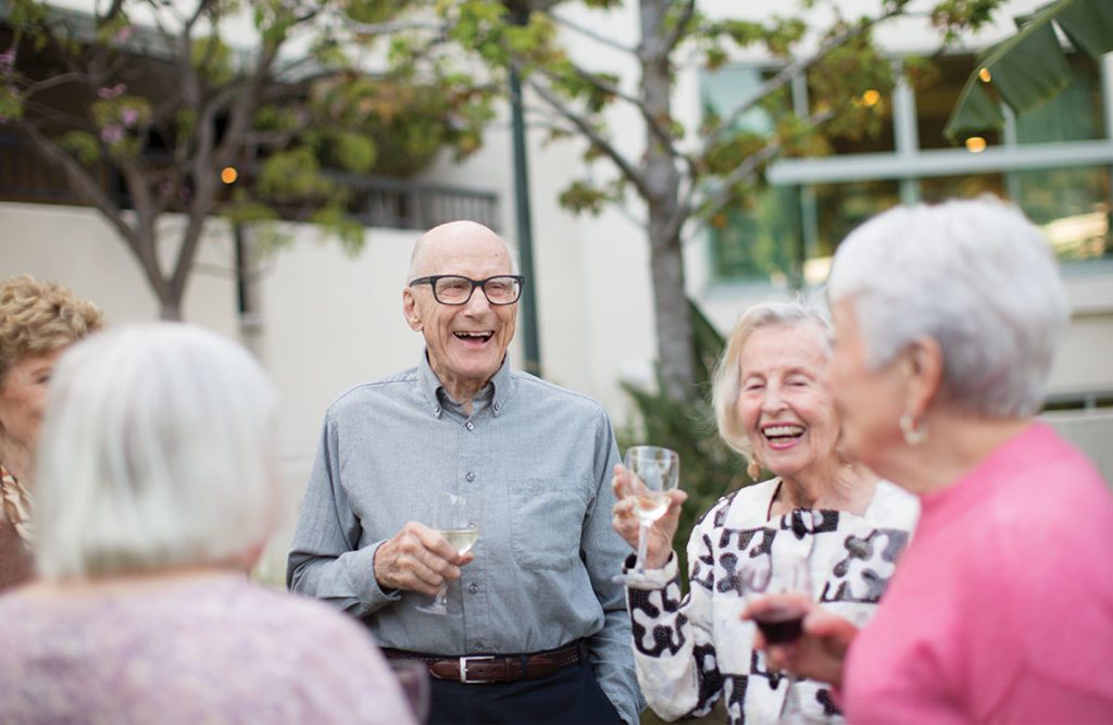 a group of elderly people drinking a glass of wine and celebrating