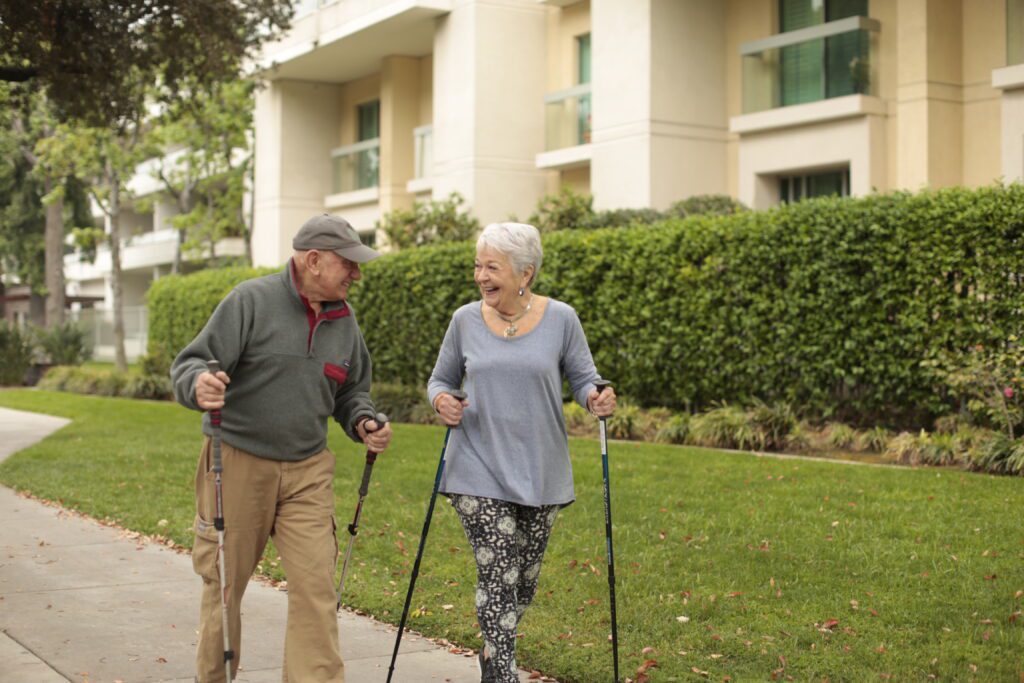 an elderly couple walking on the outside and smiling at each other