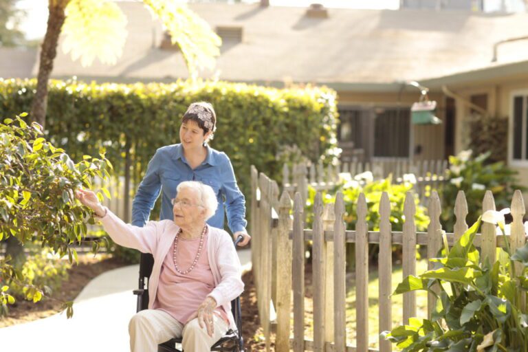 a lady walking an senior woman in a wheelchair