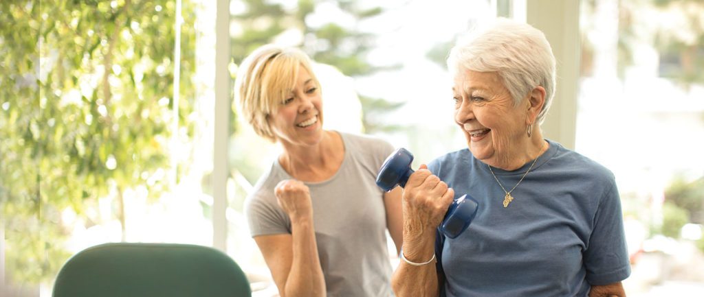 an elderly woman exercising with her instructor 