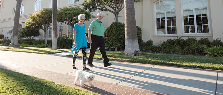 Portrait of couple walking their dog on a sunny day at Carlsbad by the Sea