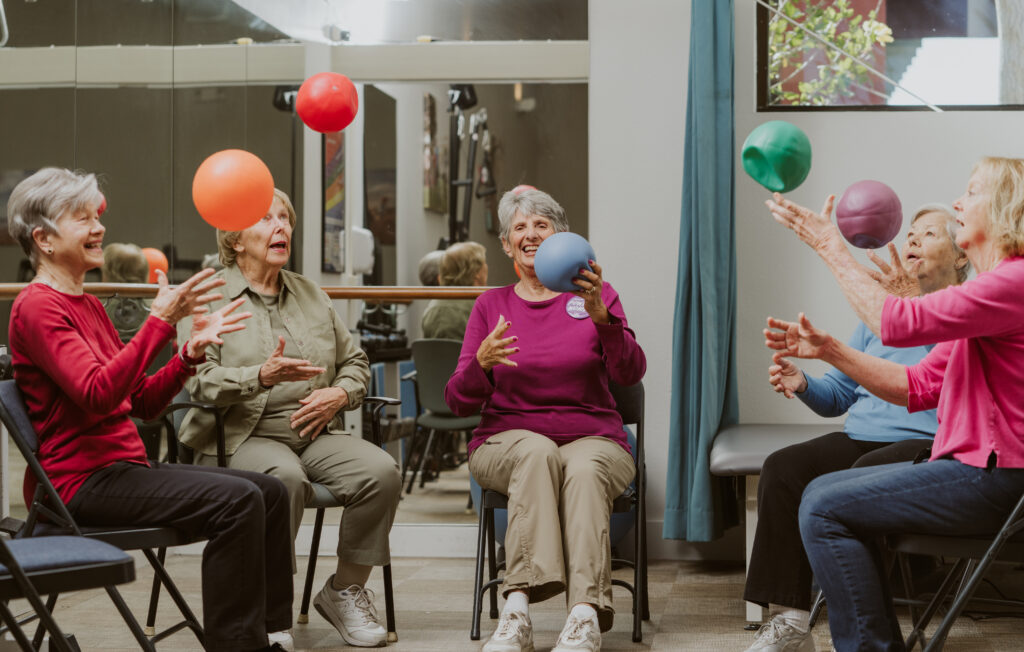 a group of elderly people having fun launching balloons into the air 