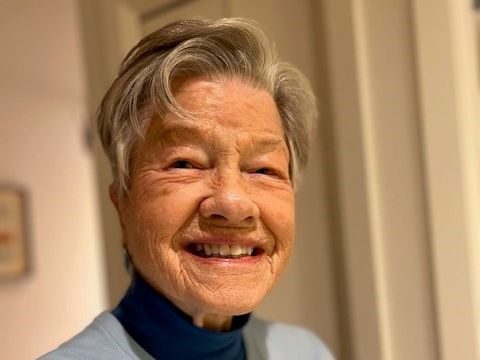 An older woman with short grey hair smiles for the camera.