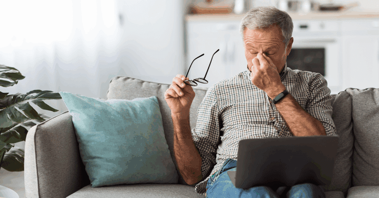 an older adult looking tired while watching the computer