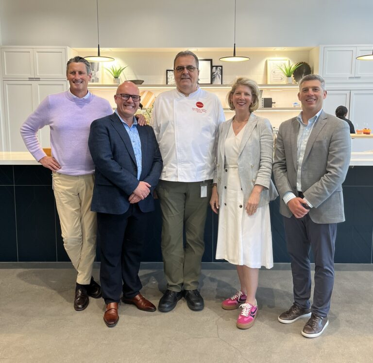 Five people stand together in front of a counter.