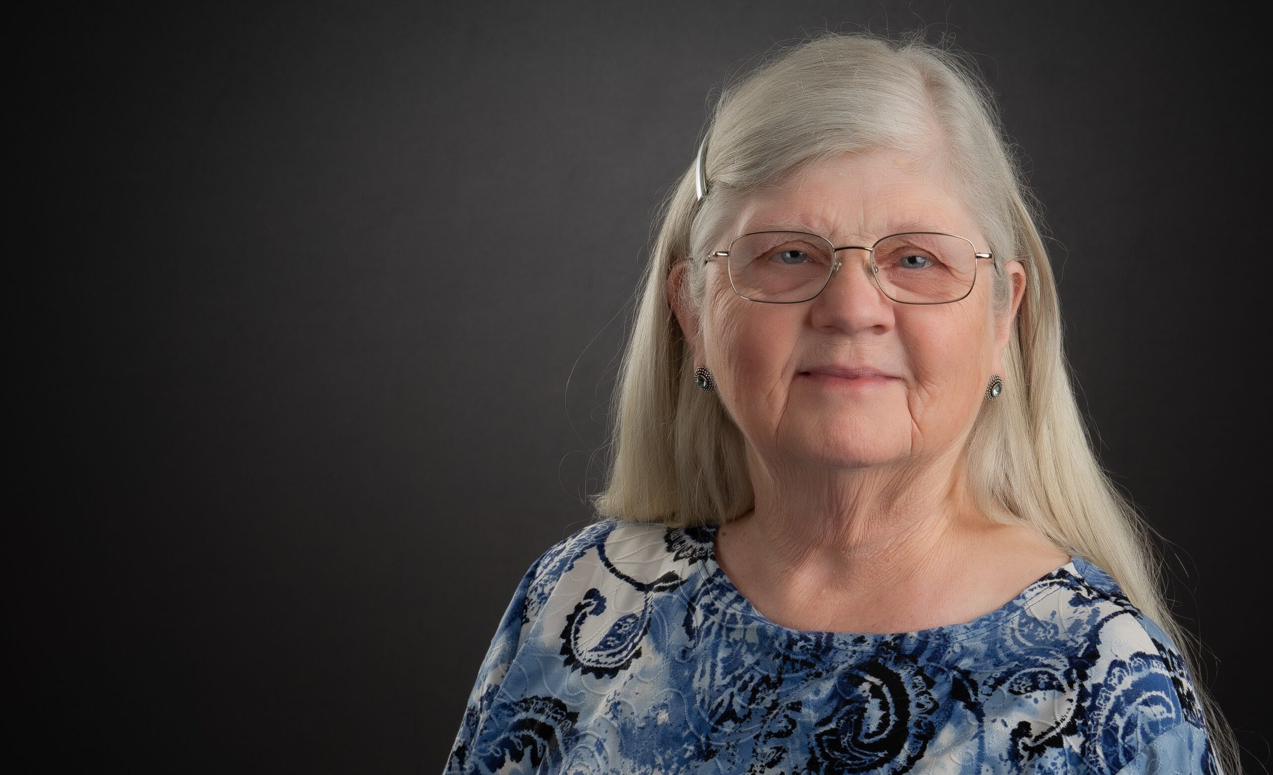 An older woman wearing a blue patterned shirt.