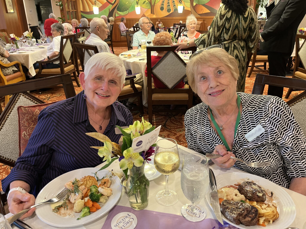 Two older women sit at a dining room table in a dining room.
