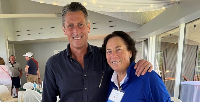 Caucasian Man Stands With Arm Around Older Woman Wearing Blue Shirt
