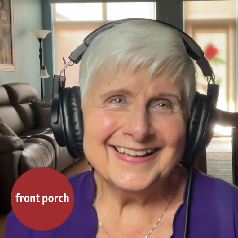 An Older Woman Smiles In A Living Room While Wearing Headphones.
