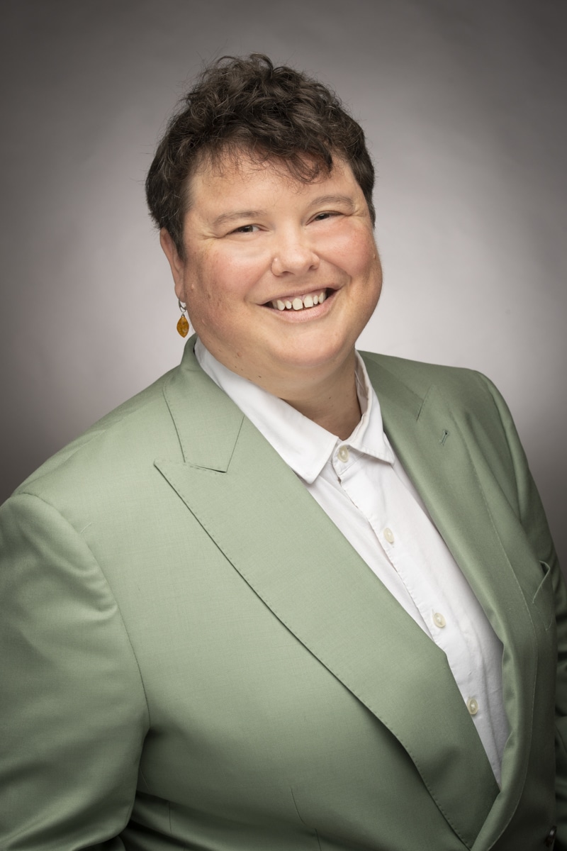 Home Match 10 A Person With Short Hair Wearing A White Shirt And Pale Green Blazer.