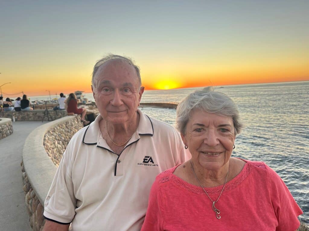 Purpose, Perspective, And P.l.u.c.k.: How Joe And Carol Danks Turn Philosophy Into Local Impact 1 Two Older Adults Stand In Front Of The Ocean At Sunset.