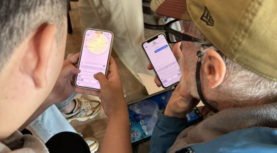 Younger and older person sit next to one another with smart phones