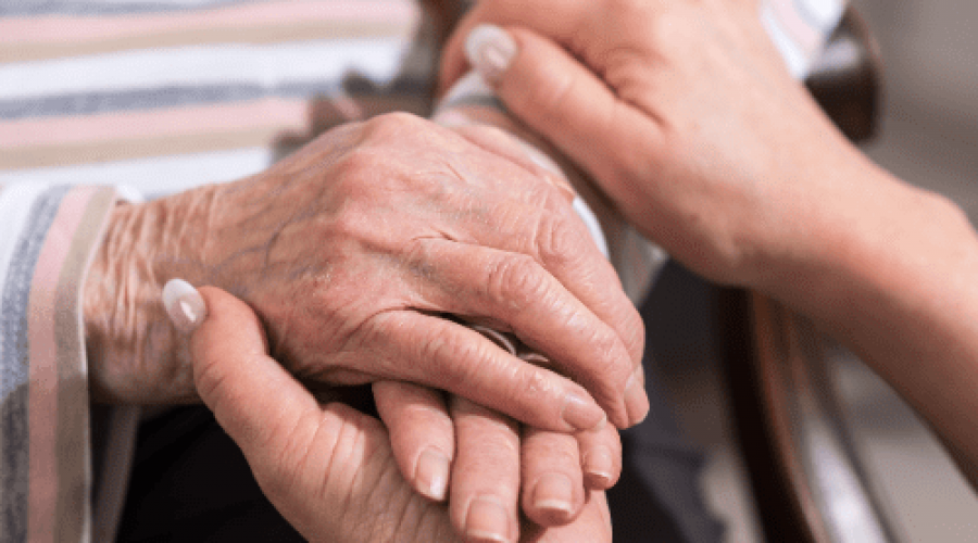 Elderly man holding womans hand for comfort