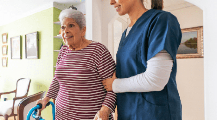 nurse helping elderly lady with a walker