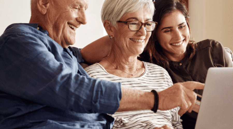 daughter looking at a computer on the couch with her elderly parents